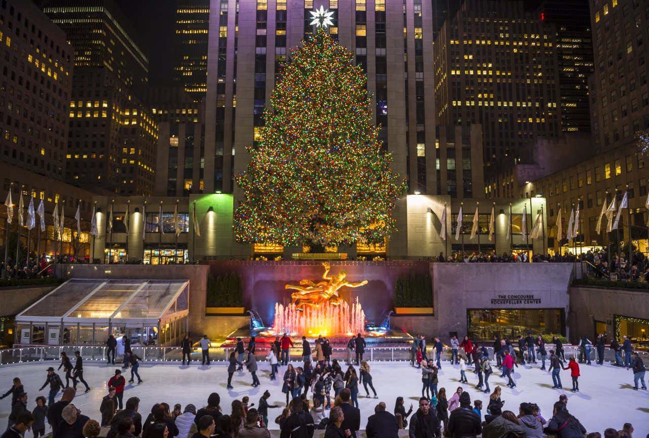 Views of Rockerfeller Christmas tree in New decorated with lights and people skating on the ice rink.