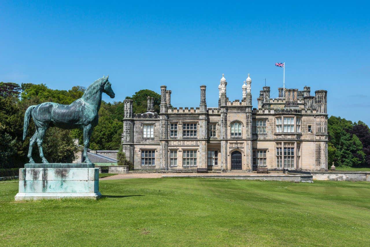 View of Dalmeny House and green lawn with horse statue in the foreground