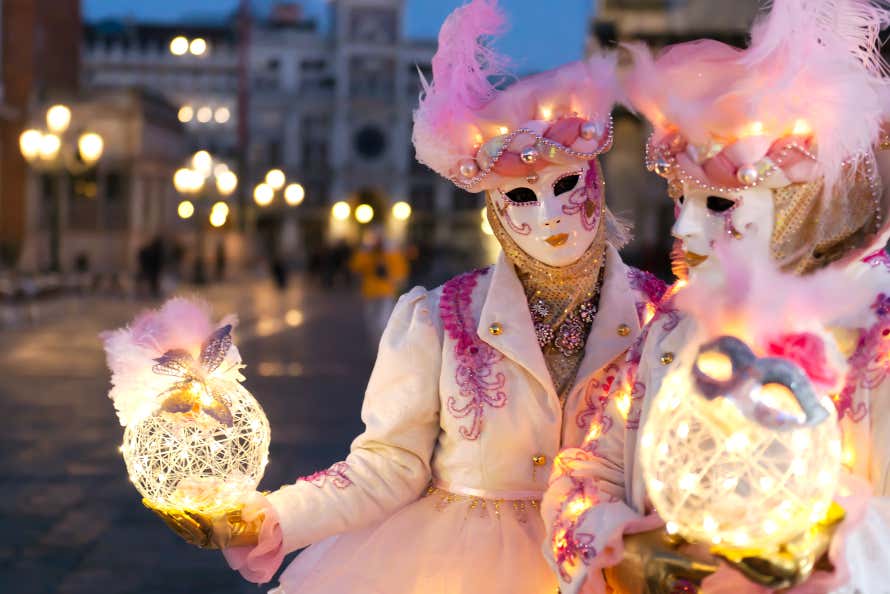 Two people dressed up, holding light nests in Venice