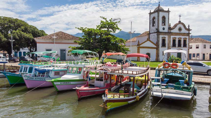 Barcos ancorados no porto de Paraty, com uma igreja de fundo