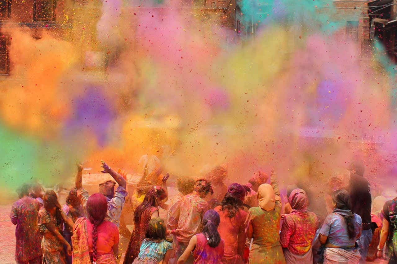 Mujeres lanzando polvos de colores al aire