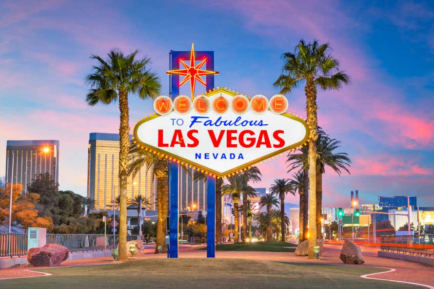L'iconica insegna luminosa di Las Vegas, con grattacieli ed edifici sullo sfondo al tramonto