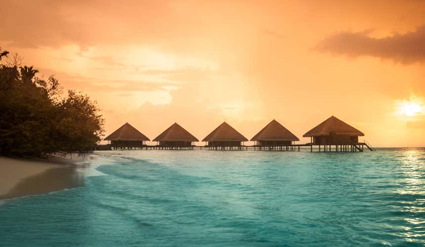 Capanne in fila sul mare a Bora Bora al tramonto