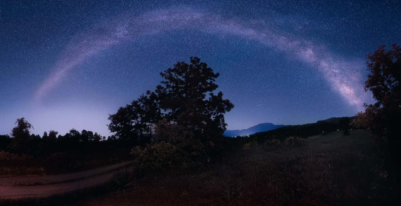 La Vía Láctea en la noche brilla en el Parque Natural de Gredos, repleto de árboles