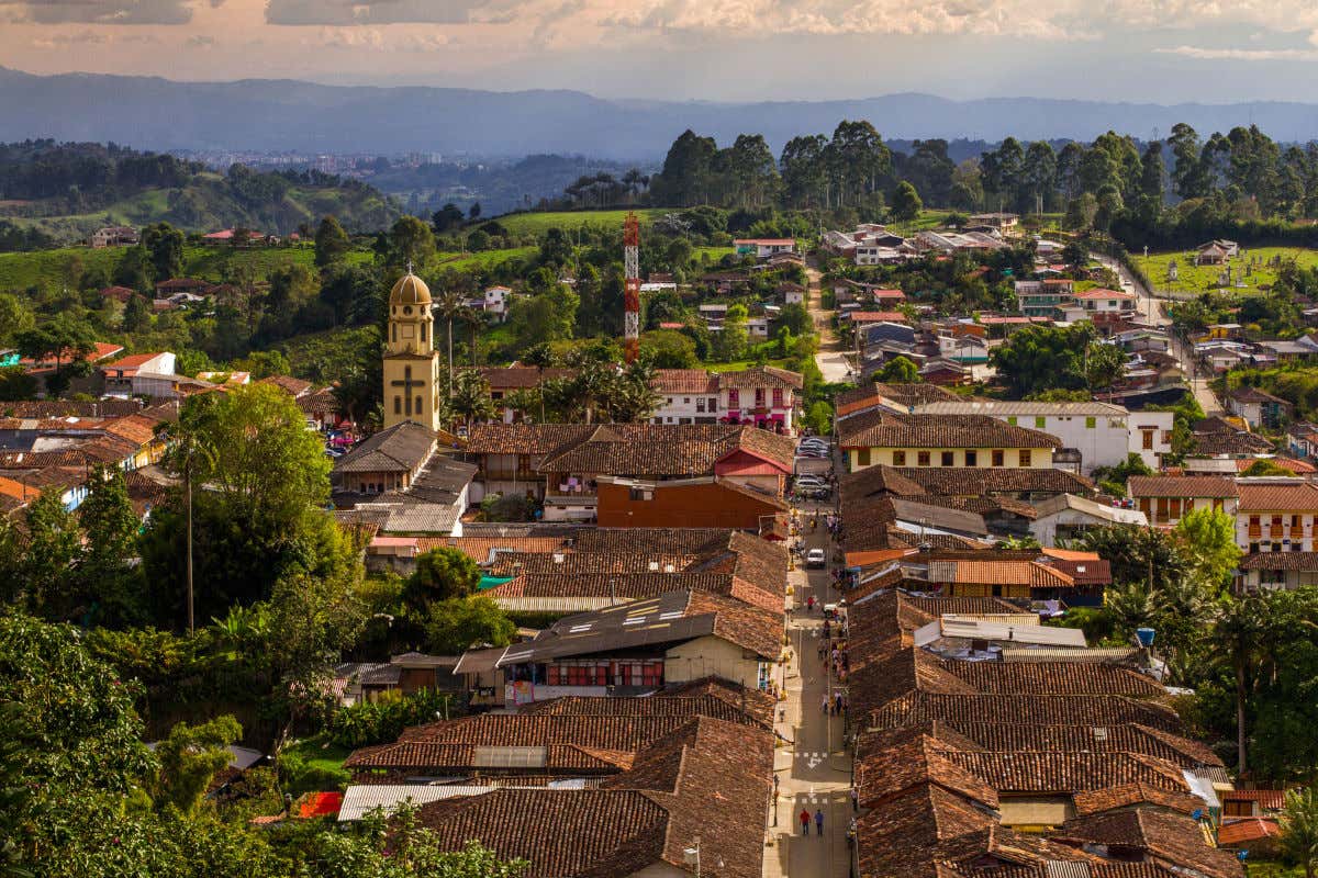 Vista aérea de una de las calles principales de Salento con la iglesia destacando en el centro del pueblo y las montañas de verde vegetación al fondo