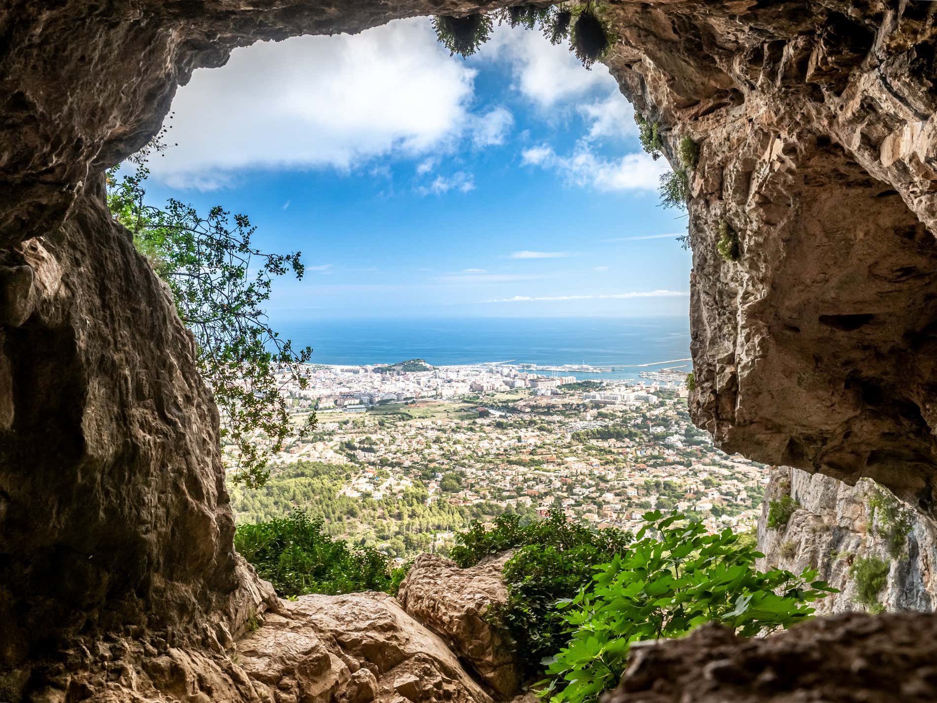 A view between rocks over houses towards the sea in the Region of Valencia on a bright day