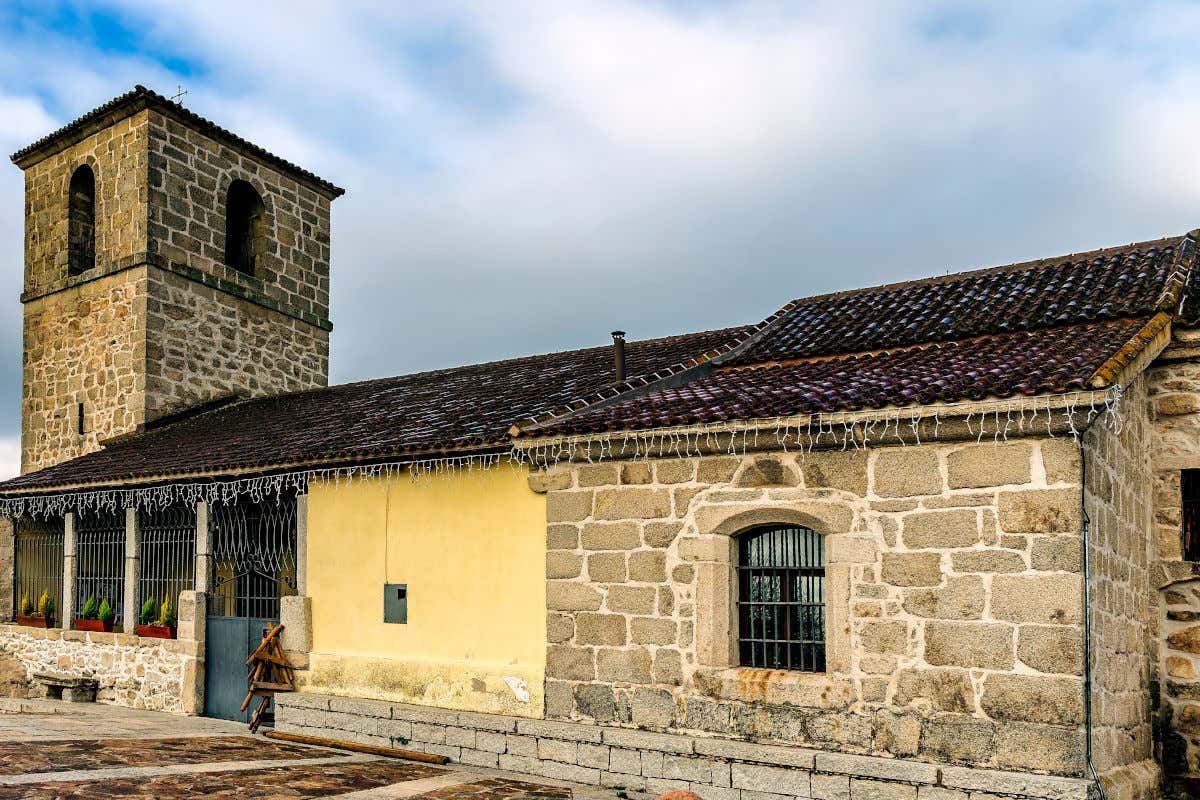 Fachada de piedra con una pequeña torre de la iglesia de Santo Tomás Apóstol en El Berrueco