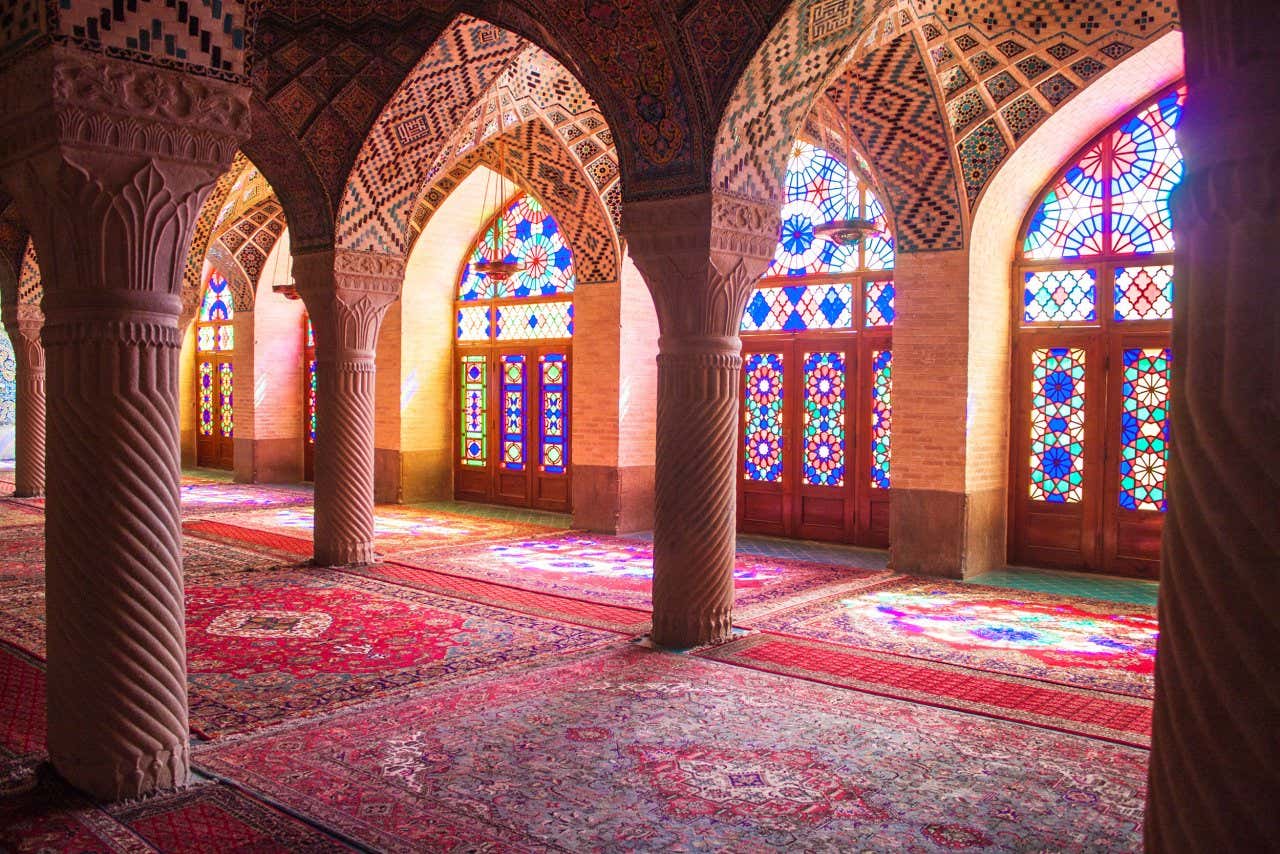 Intérieur de la mosquée aux tons rouges et roses accentués par la lumière entrant par les vitraux du temple