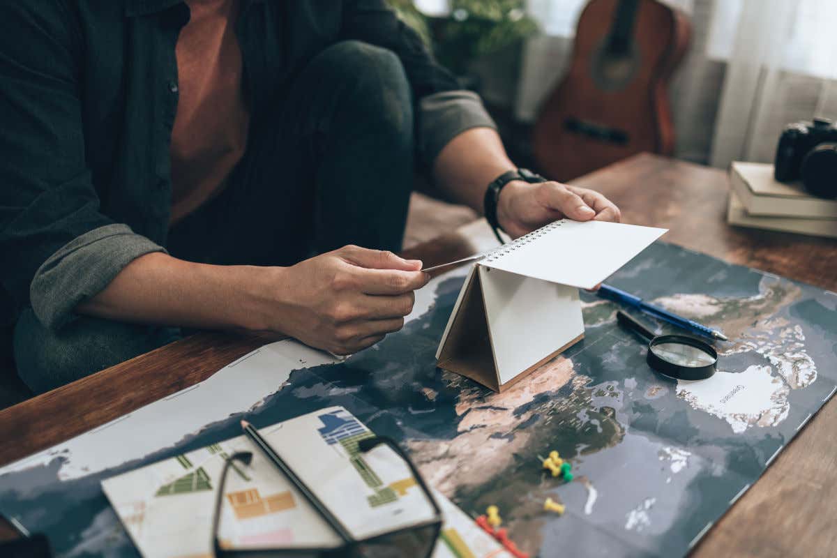 Una mesa con un mapa, lupa y calendario en una habitación ocupada por un viajero que trata de organizar sus vacaciones