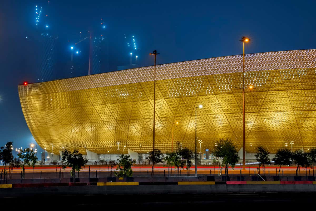 Exterior del campo de juego futbolístico Lusail de Qatar iluminado con tonos dorados al caer la noche