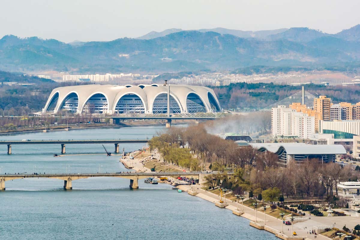 Panorámica del Rungrado Primero de Mayo de Pyongyang, el estadio más grande del mundo junto a un río y varias montañas