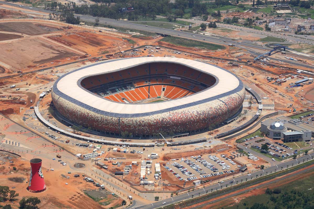 Panorámica del estadio Soccer City de Johannesburgo rodeado de terrenos sin construcciones que sirven de parking para varios vehículos