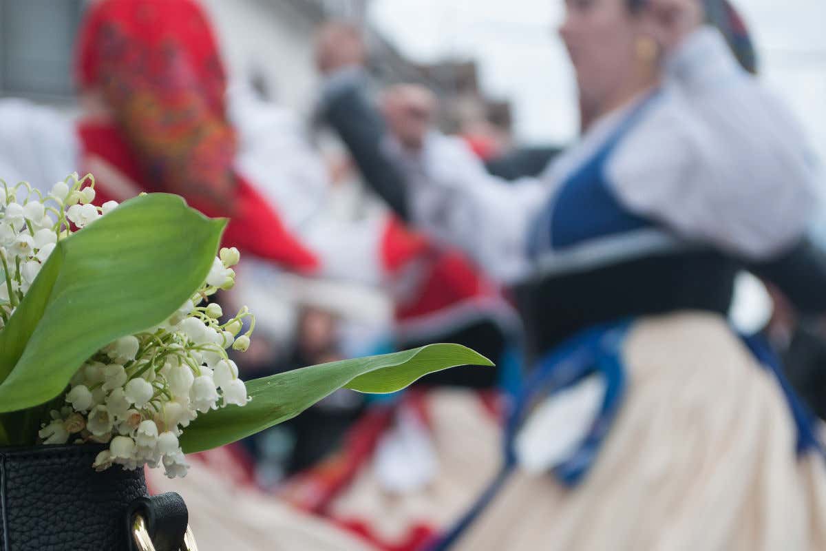 Un arreglo arreglo floral frente a un grupo de personas bailando con trajes tradicionales de Alsacia