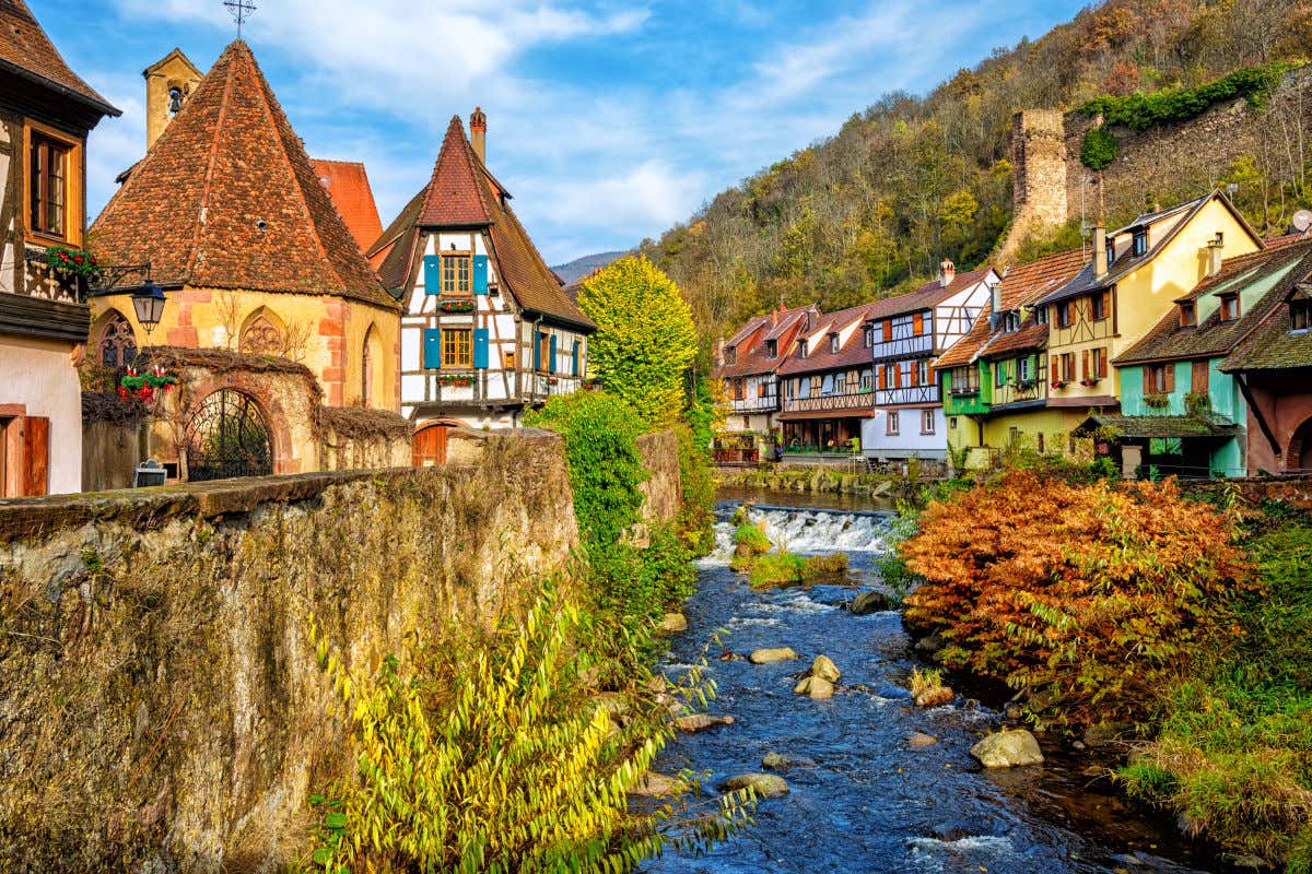 Un río atravesando el pueblo de Kaysersberg, con sus casas e iglesias cerca de las orillas de la corriente fluvial