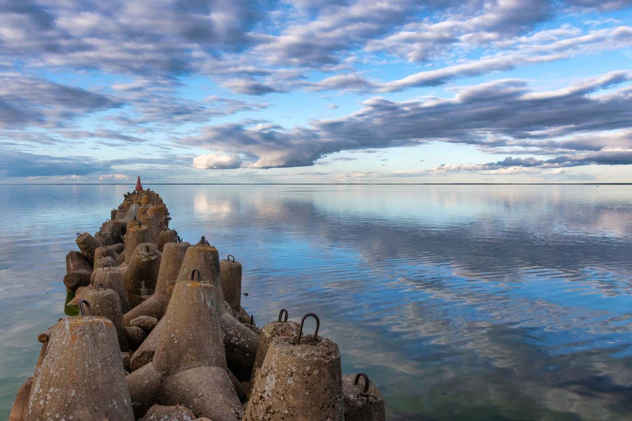 Vista del rompeolas en el lago Beloye con varias nubes reflejadas en el agua del manantial 