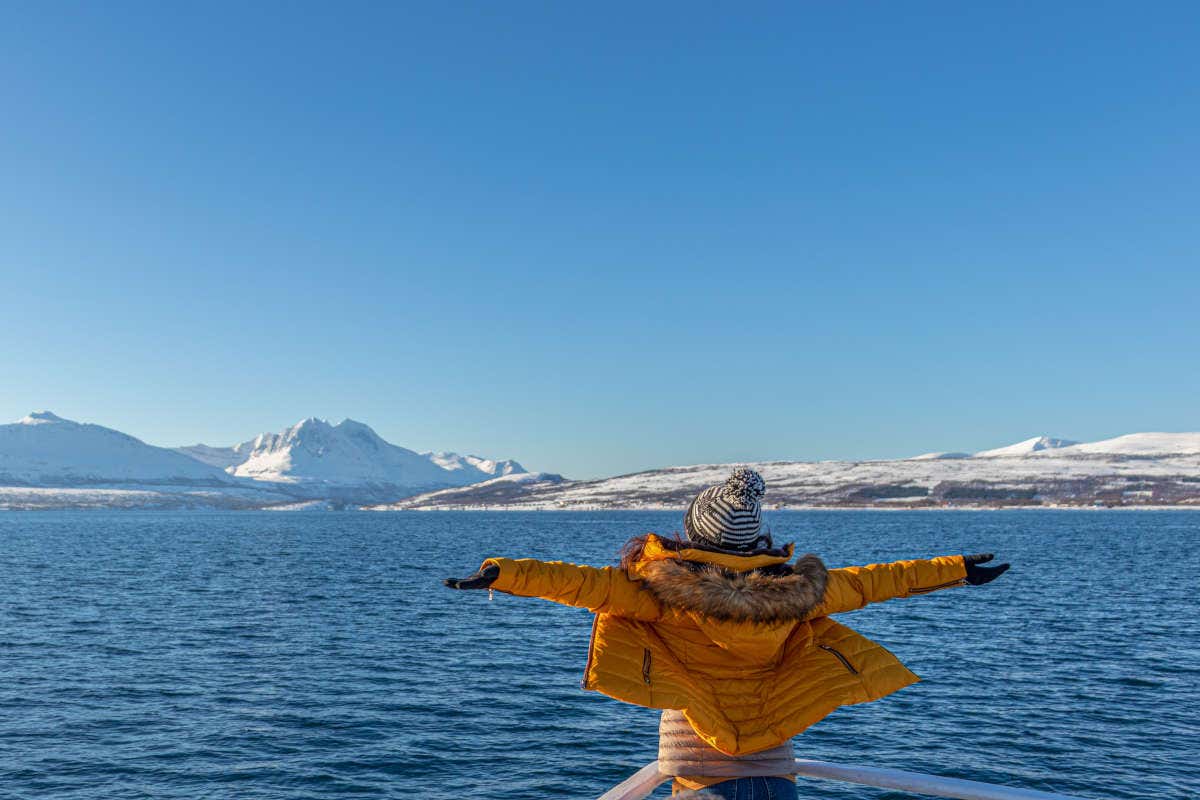 Una mujer con los brazos abiertos en los fiordos noruegos