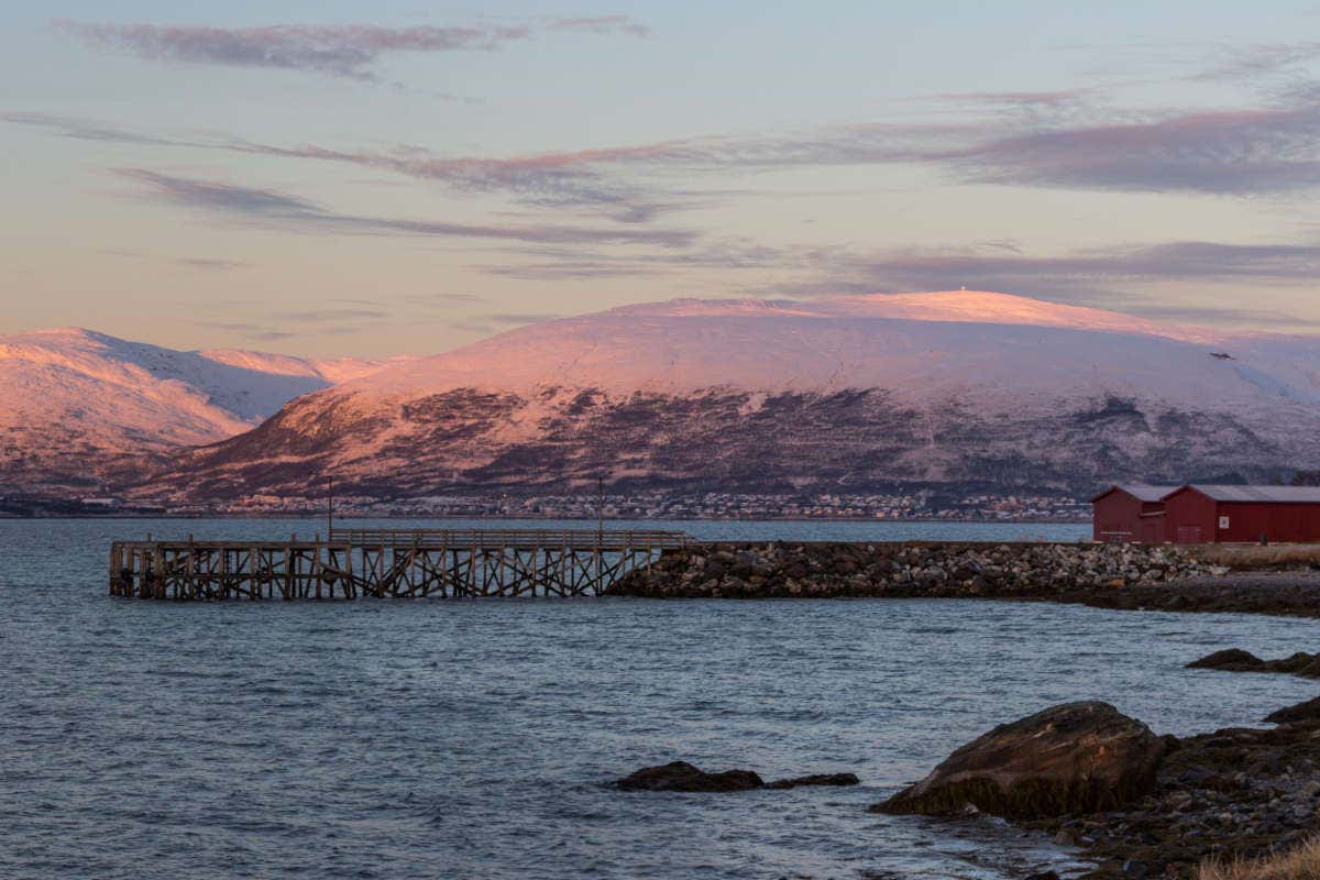 Montañas nevadas teñidas de morado por el atardecer sobre la playa Telegrafbukta, 