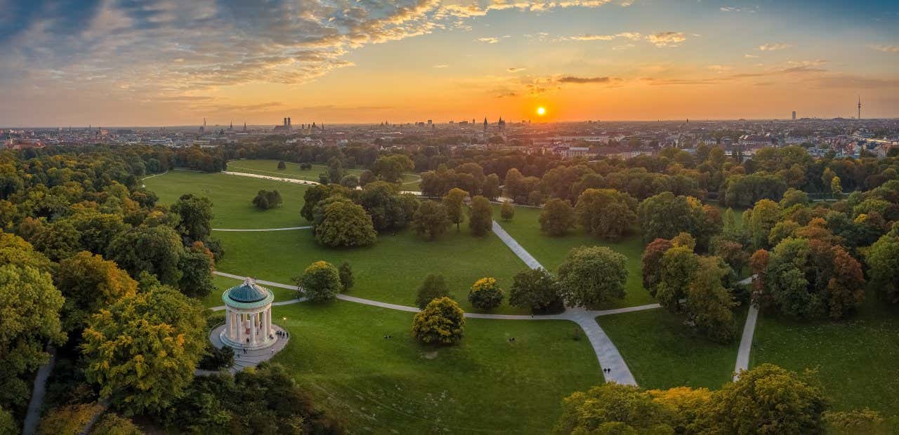 Vue panoramique sur un parc verdoyant avec la ville en arrière-plan au coucher du soleil