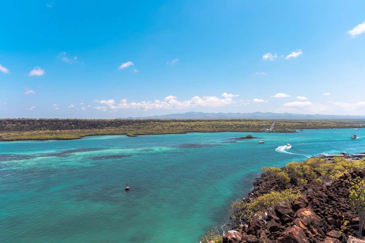 Águas do canal de Itabaca, que separa a ilha Baltra da ilha de Santa Cruz e barcos navegando pelo centro