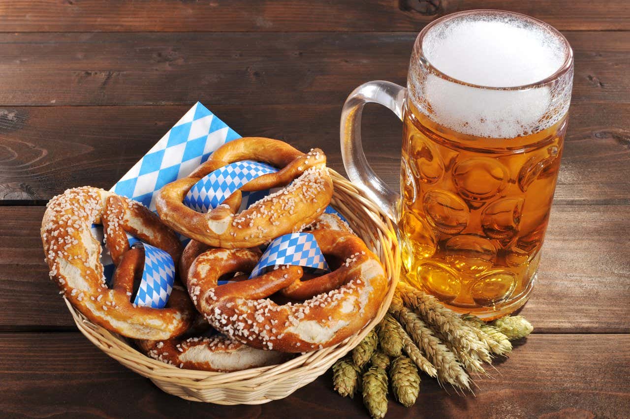 Uma jarra de cerveja e os típicos bretzel com um guardanapo com as cores da bandeira da Baviera