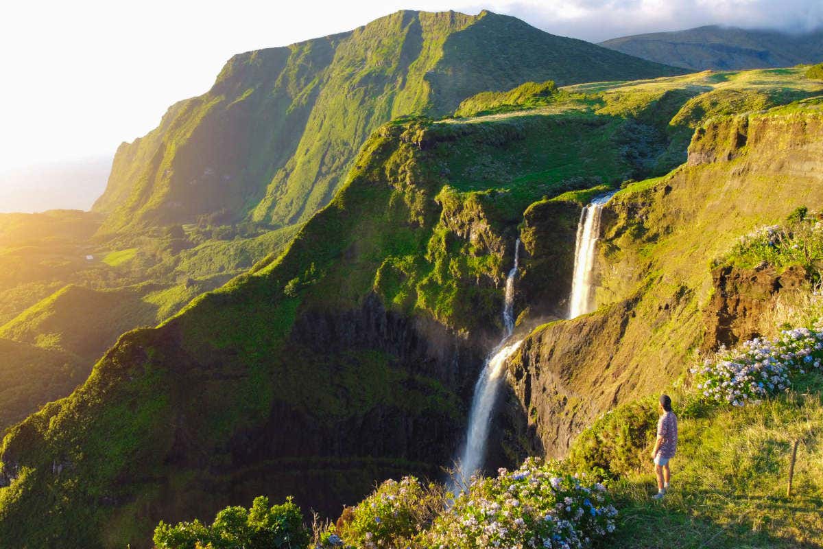 Un chico contemplando una enorme cascada en la isla de Flores