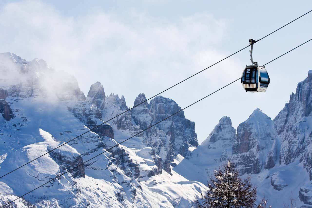 Primo piano sulla funicolare di Madonna di Campiglio, con le cime innevate sullo sfondo, in una giornata di sole