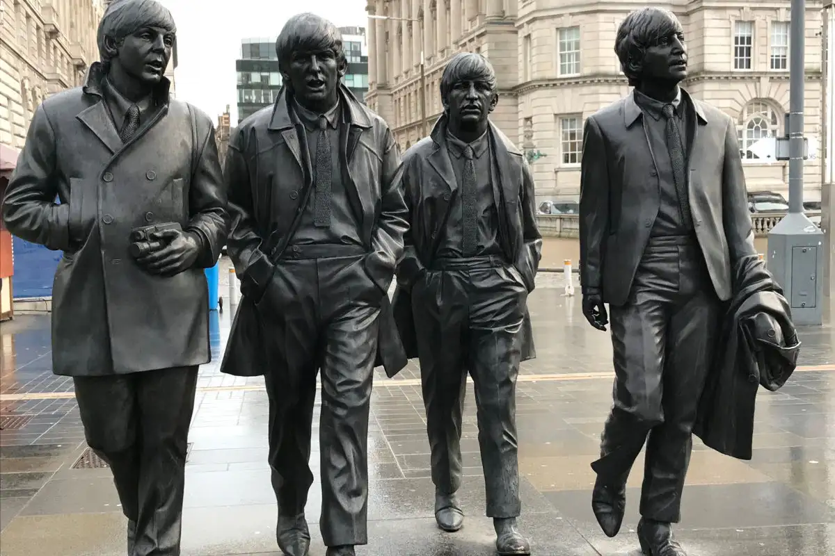 Statue dei quattro membri dei Beatles in una strada di Liverpool in una giornata piovosa