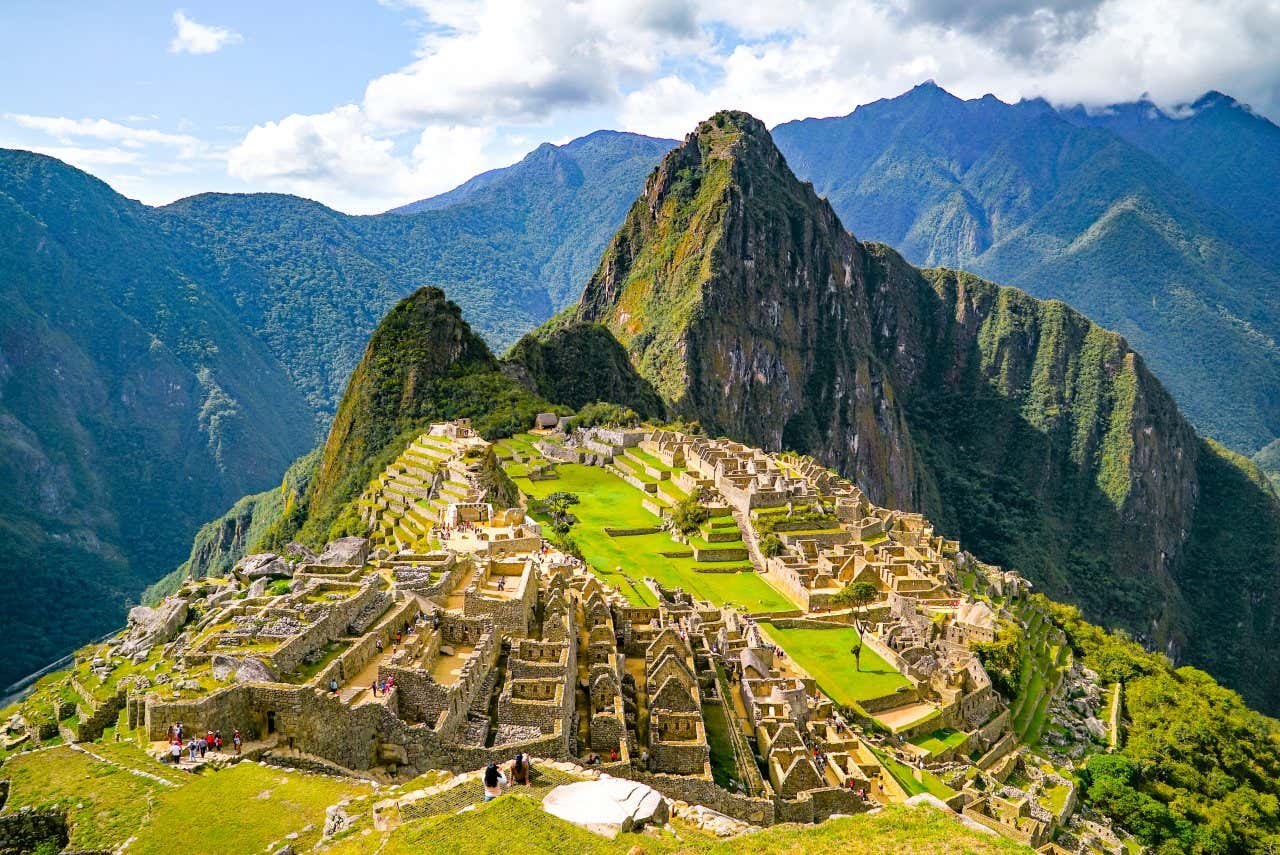 Vista panoramica sulle rovine di Machu Picchu in Perù, in una giornata di sole, con imponenti montagne sullo sfondo