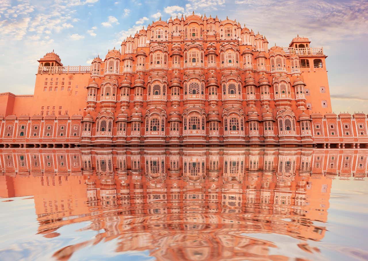 Façade du palais des vents de couleur orange avec son reflet dans l'eau, l'un des plus beaux palais du monde