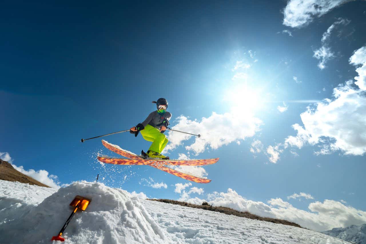 Personne faisant un saut à skis dans la montagne sous un ciel ensoleillé avec quelques nuages, une option pour skier en Espagne