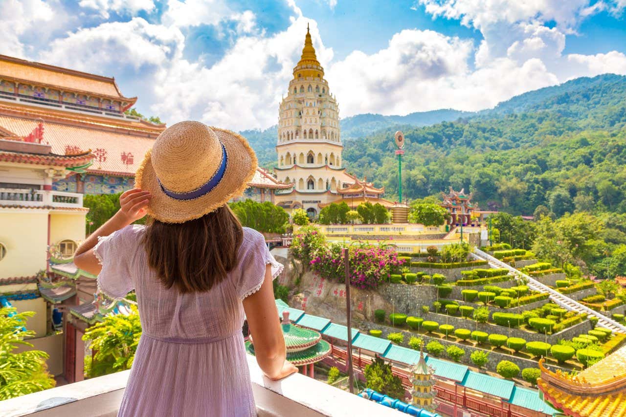 Una ragazza di spalle, ammira il tempio di Kek Lok Si a Georgetown, circondato dalla vegetazione e da alcuni giardini decorativi