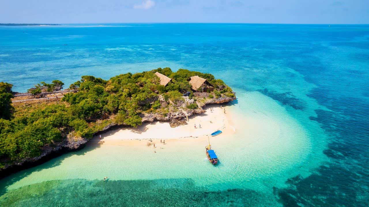 Vista panoramica su una paradisiaca baia di Zanzibar, con acque cristalline, folta vegetazione e un paio di barche vicino alla costa