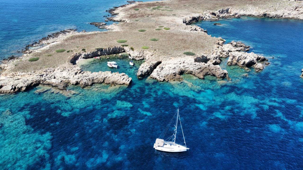 Vue aérienne sur la baie de Port d'Addaia avec ses rochers typiques de la zone et un voilier naviguant paisiblement