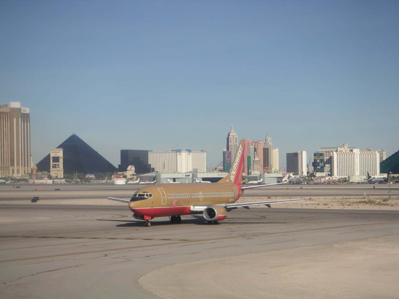 Un avión dorado y rojo en primer plano, con el horizonte de Las Vegas en el fondo, incluida la Pirámide Luxor