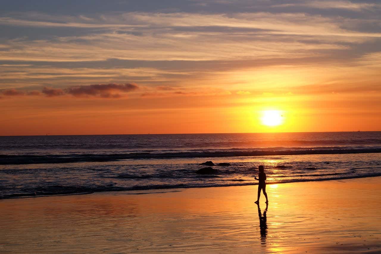 Figura di un bambino che cammina sulla battigia di Coronado Beach al tramonto