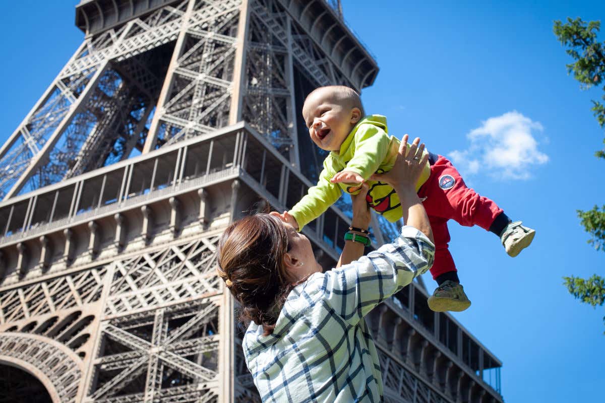 Una donna che tiene in braccio un bambino davanti alla Torre Eiffel