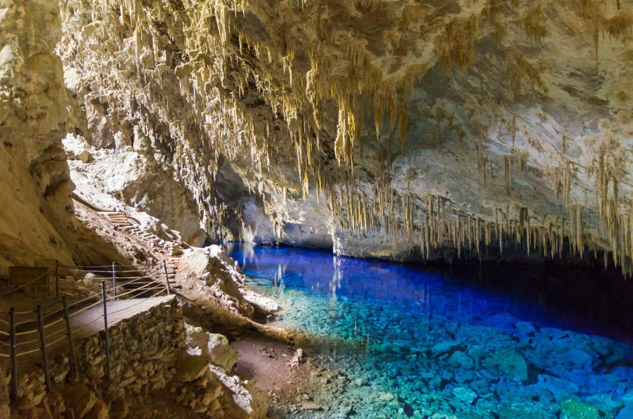 Uma das grutas de Bonito com água azul-turquesa repleta de estalactites no teto