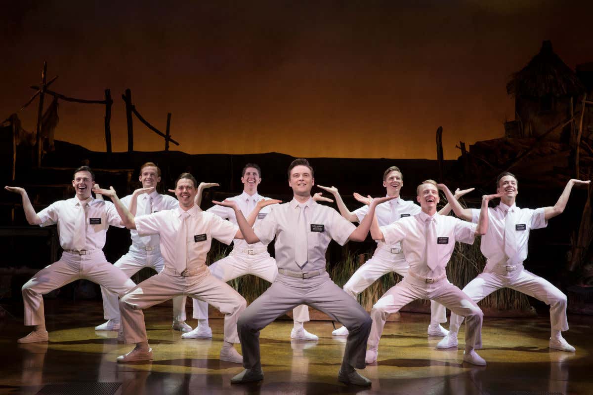 Des danseurs entièrement vêtus de blanc sur une scène de théâtre interprétant The Book of Mormon