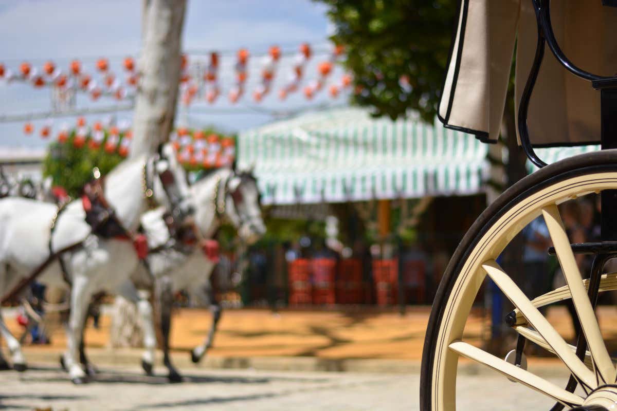 Detalle de la rueda de una carroza de caballos frente a una caseta de la Feria de Abril, en Sevilla