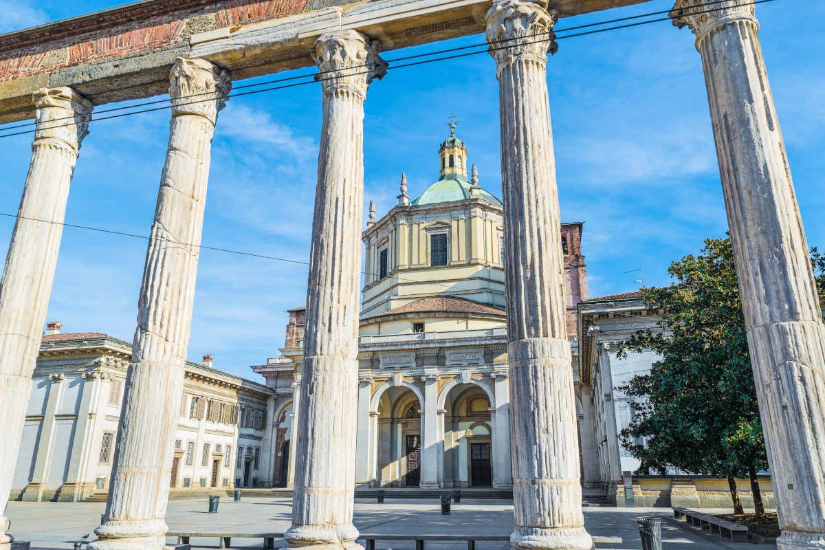 Cinco enormes columnas de piedra en una plaza frente a una iglesia