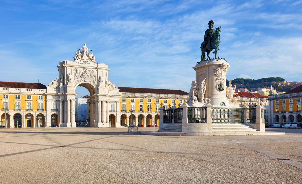 A square with a sculpture of King José I in the centre and yellow buildings in the background and the Rua Augusta Arch.