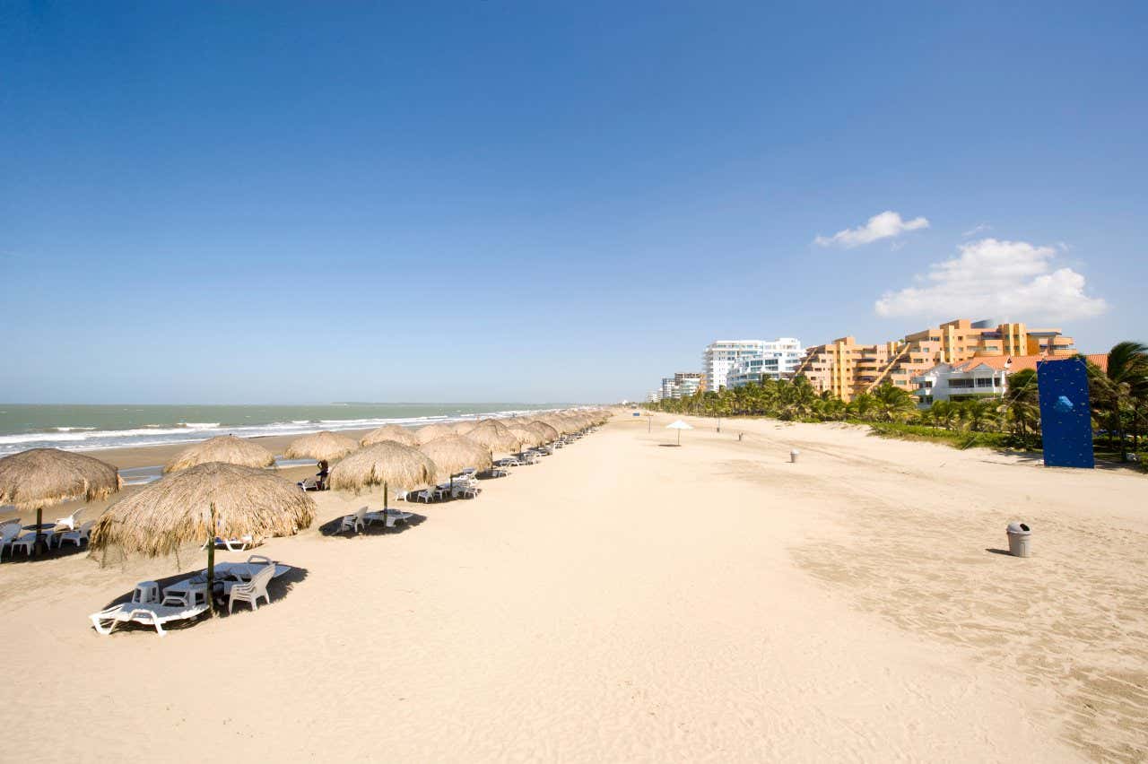 Faixa de areia da praia La Boquilla em um dia claro com espreguiçadeiras e guarda-sóis, em Cartagena de Índias