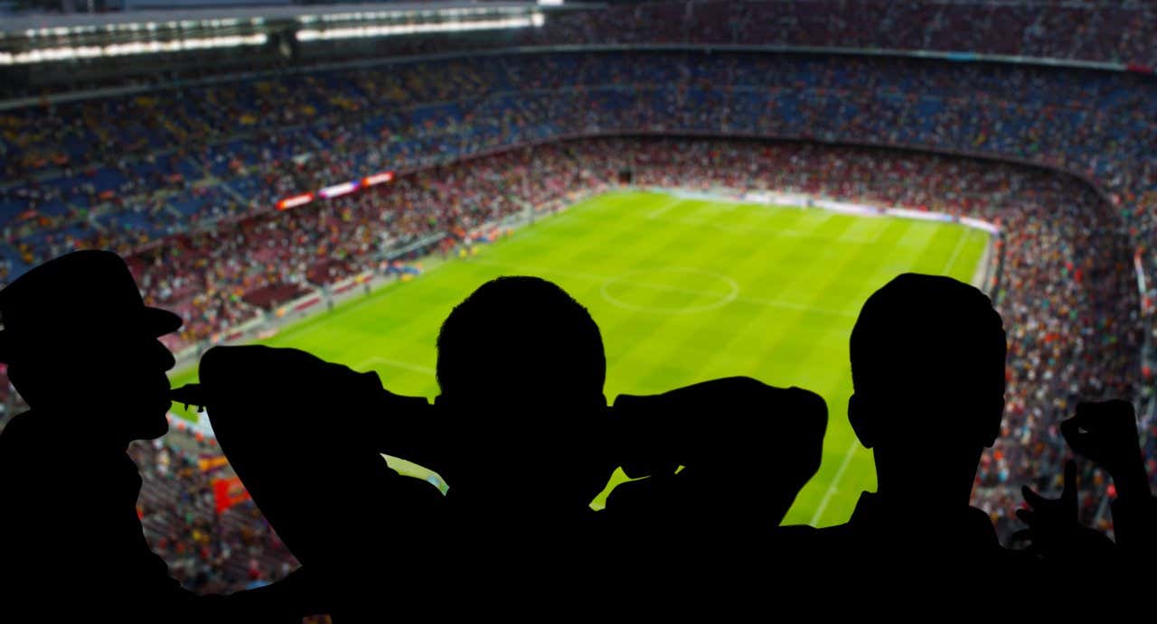 Vue sur le Camp Nou depuis les gradins du parc, avec trois personnes dans l'ombre au premier plan