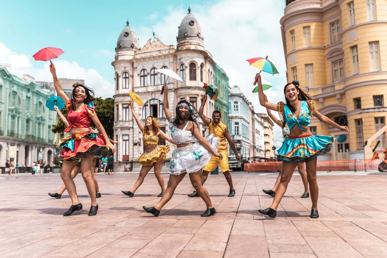 Sete dançarinos vestidos com roupas típicas de frevo dançando no centro do Recife