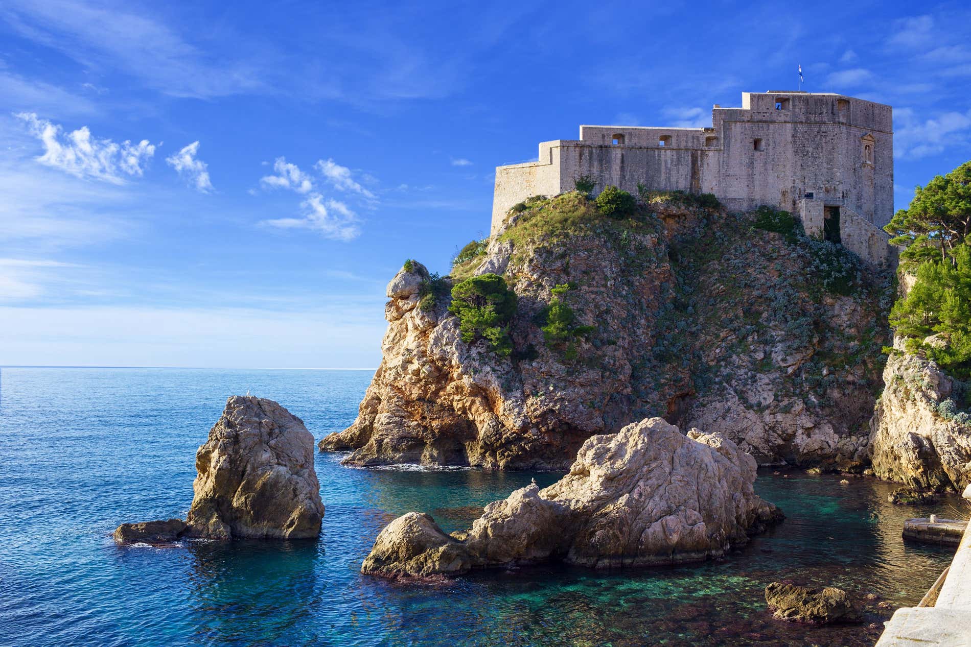 Forte Lovreijenac, la Fortezza di San Lorenzo in Croazia vista dal basso con mare cristallino e alcuni scogli che spuntano dall'acqua