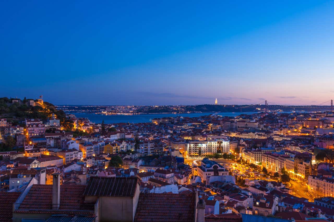 An aerial view of Lisbon at Dusk with a clear purple sky at the top.