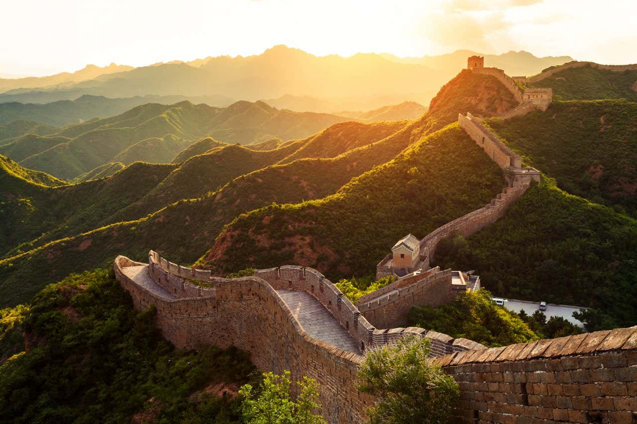 An aerial view of the Great Wall of China with the sun setting in the background.