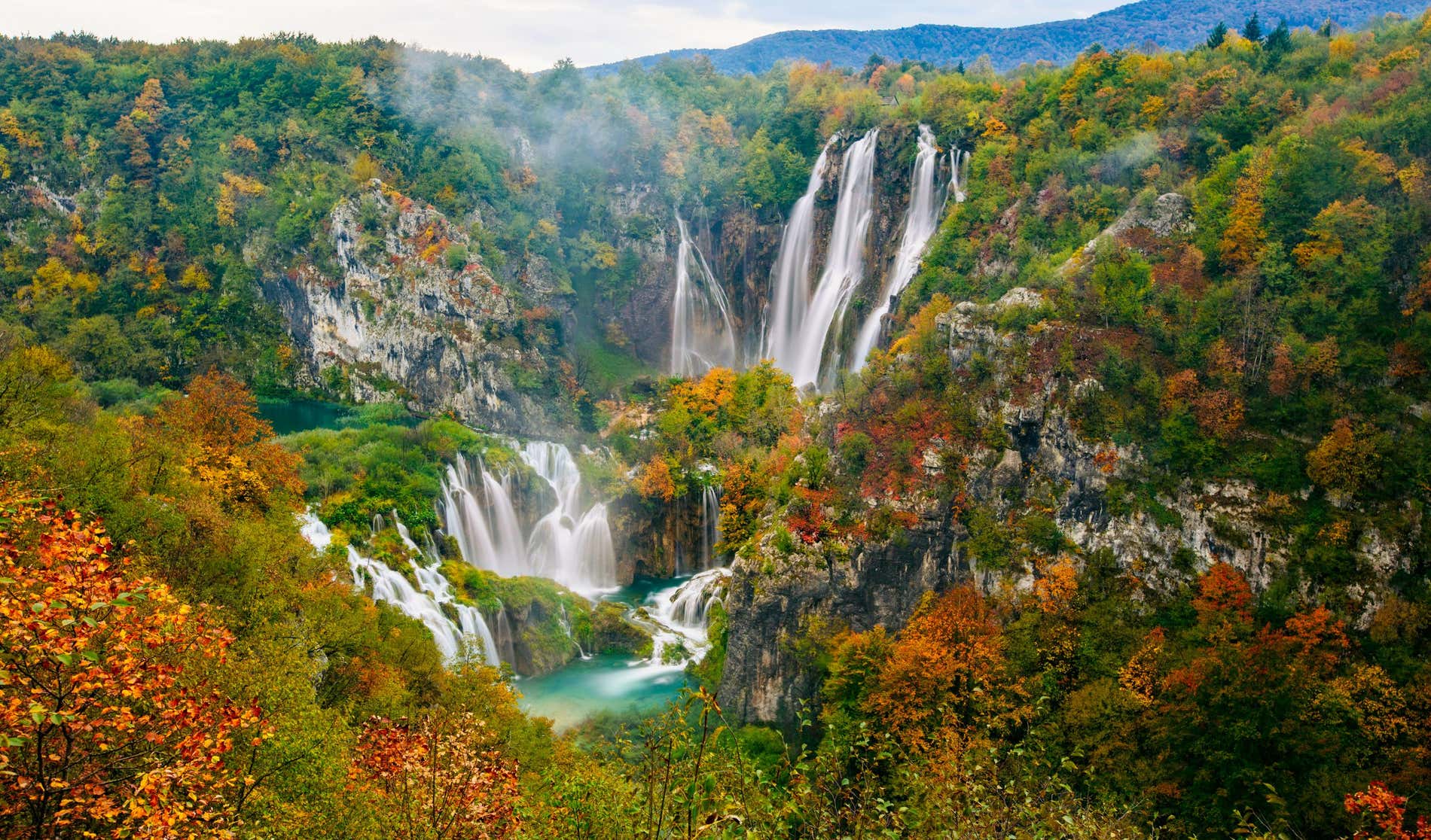 Parco Nazionale di Plitvice National Park in Croazia, con alcune cascate che si tuffano in piscine naturali circondate da alberi marroni, gialli e verdi