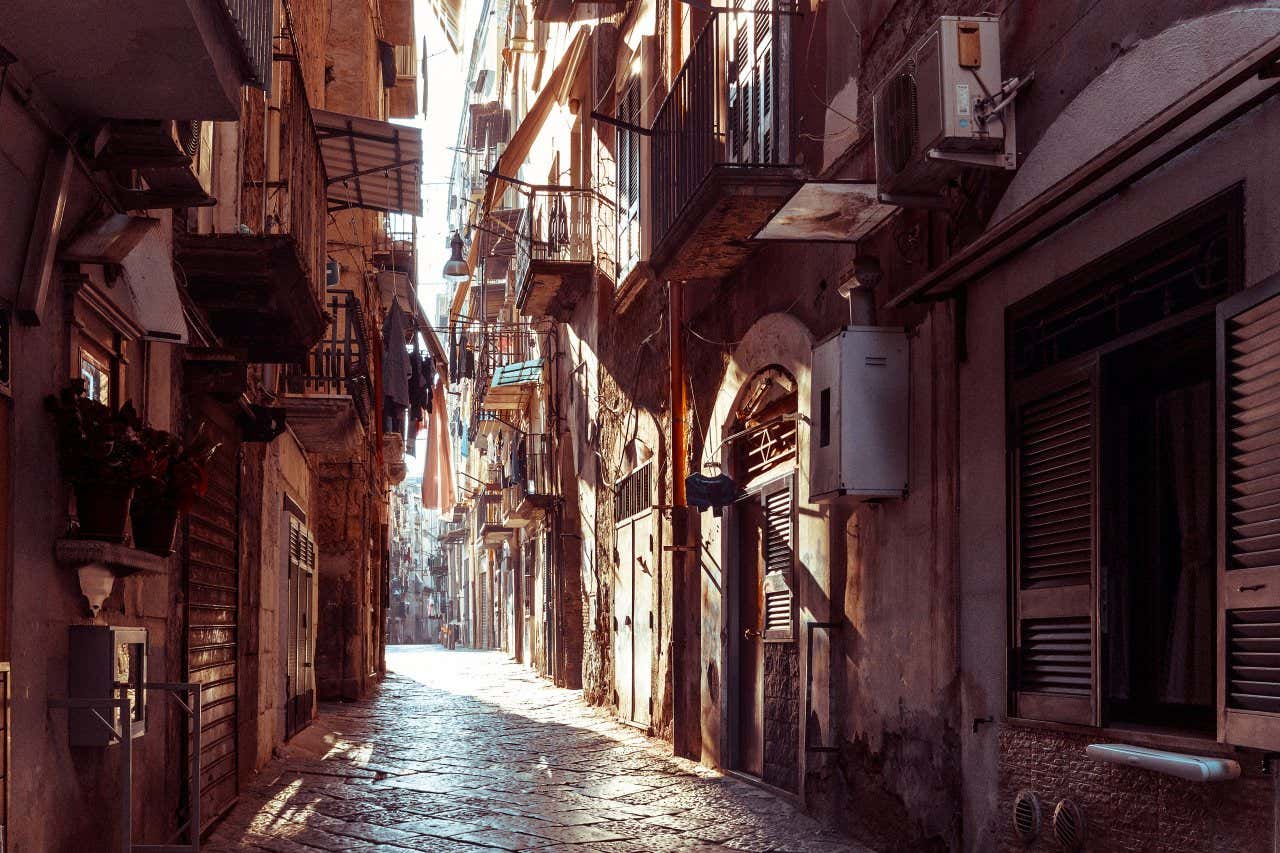 Una stretta via del centro di Napoli con panni stesi e vasi alle finestre