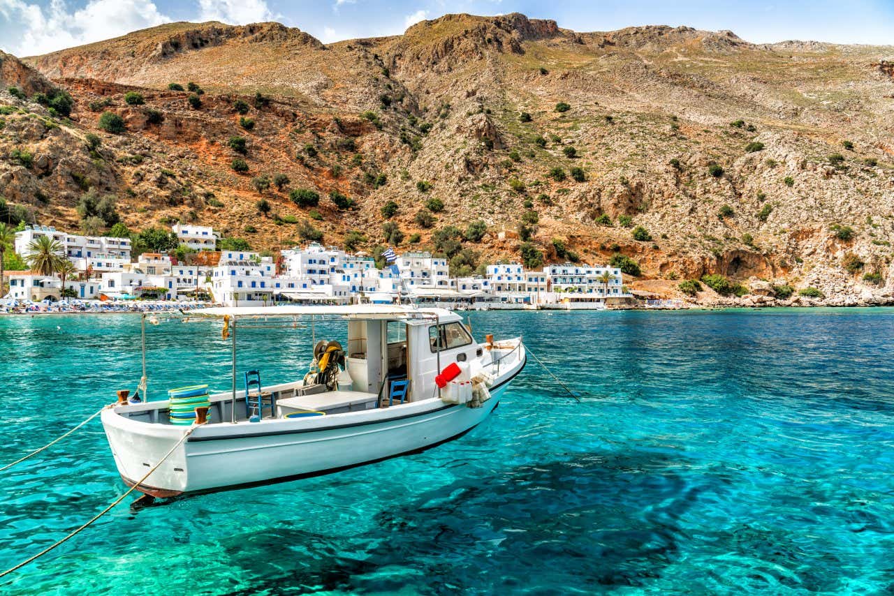 A boat sailing in Crete, Greece, with the town and a mountain in the background.